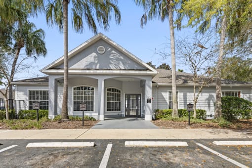 the front of a white house with palm trees and a driveway
