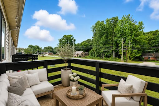 A balcony with a table and chairs overlooking a green landscape.