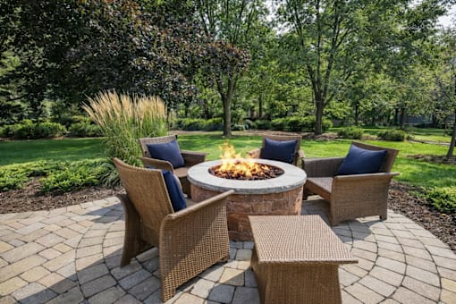 A fire pit surrounded by wicker chairs and a table.