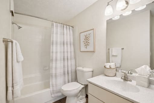 A white bathroom with a toilet, sink, and shower.