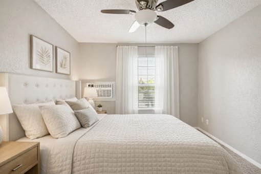 A bedroom with a large bed and a ceiling fan.