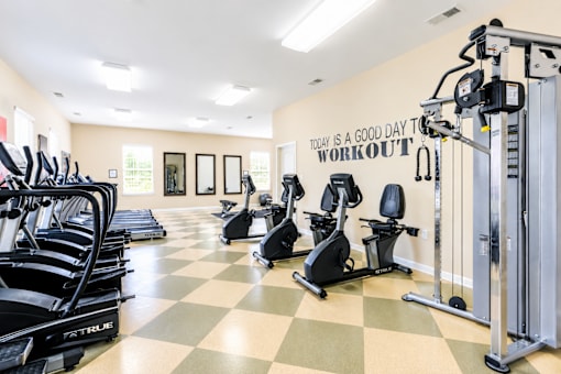 A gym with a variety of equipment including treadmills, stationary bikes, and weight machines.