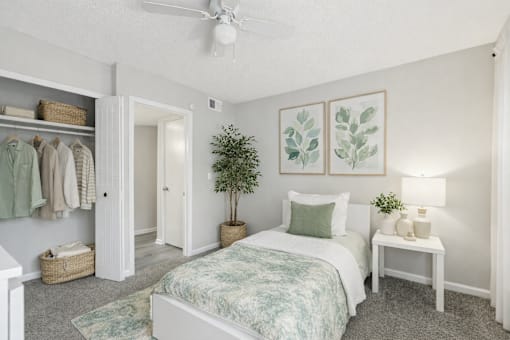 A bedroom with a bed, a nightstand, and a plant.