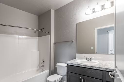 A bathroom with a white tub, sink, and toilet.