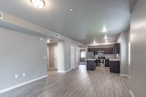 A spacious kitchen and living room with wood flooring and white walls.