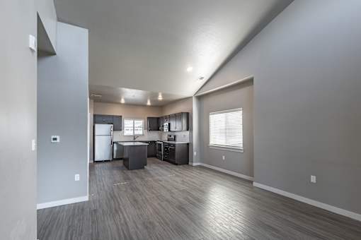 A spacious kitchen and living room with wood flooring and white appliances.