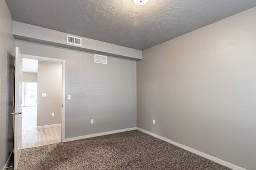 A room with a carpeted floor and a door leading to another room.