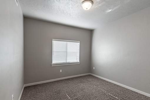 A room with a window and carpeted floor.