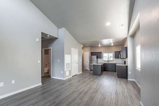 A spacious living area with a kitchen in the background.