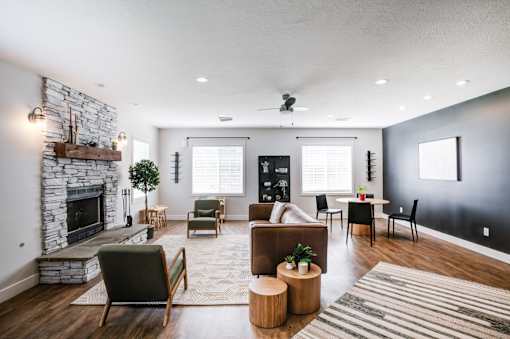 the living room has a large stone fireplace and a dining room table and chairs at Haven Pointe Apartments, West Haven, UT, 84401