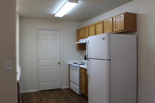 an empty kitchen with white appliances and wooden cabinets and a refrigerator