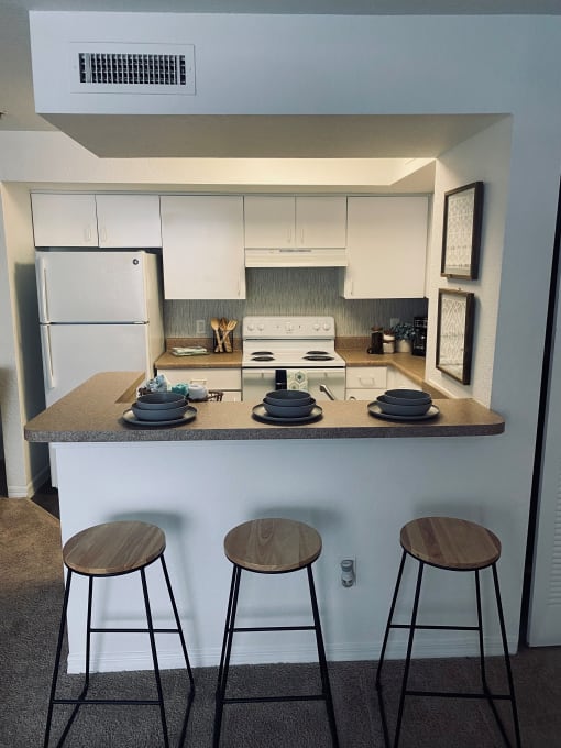 a kitchen with a counter and three stools
