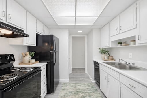 A kitchen with black appliances and white cabinets.