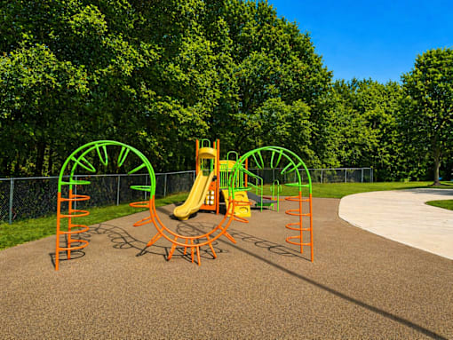 A playground with a yellow slide and green and orange climbing structures.