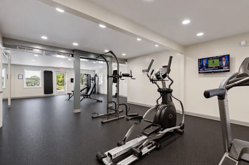 A gym with a row of treadmills and elliptical machines.