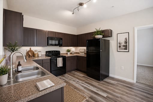 A kitchen with a black fridge and microwave.