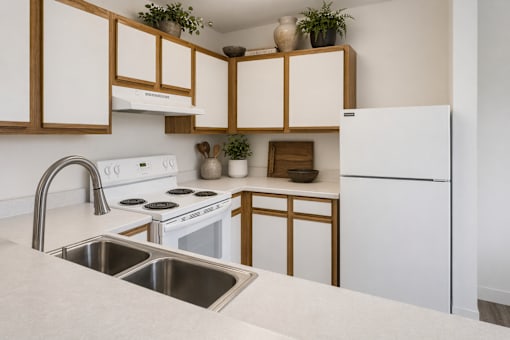 A kitchen with white appliances and wooden cabinets.