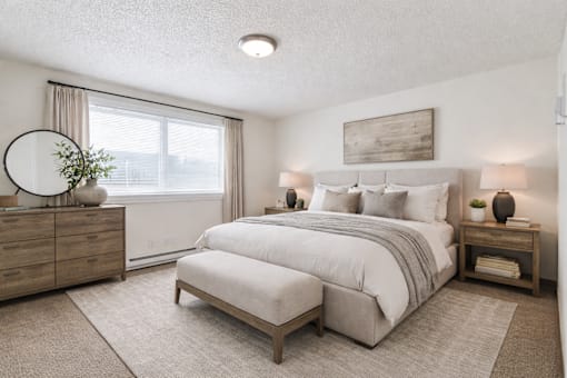 A bedroom with a large bed, a dresser, and a nightstand.
