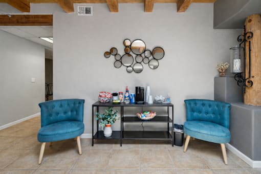 A room with two blue chairs and a table with various objects on it.
