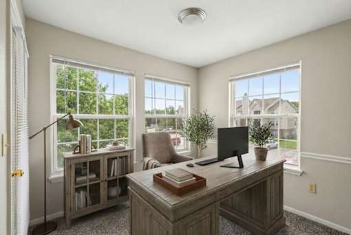 A home office with a desk, chair, and a window overlooking a residential area.