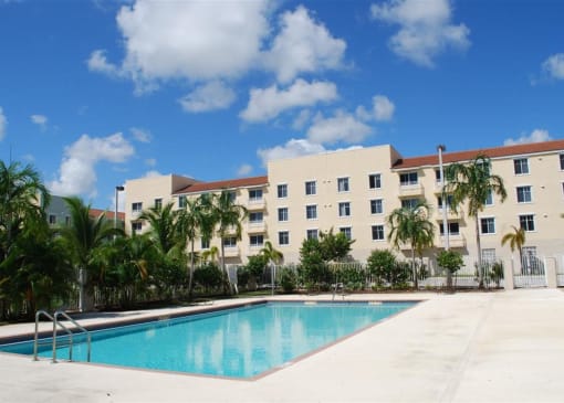 A large white building with a pool in front of it.