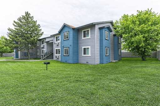 A blue and grey two story apartment building with a mailbox in front.