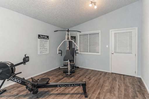 A gym room with a rowing machine and a bench.