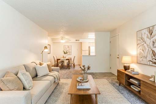 A living room with a couch, coffee table, and a dining table.
