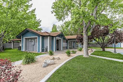A blue house with a grey roof and a white fence.