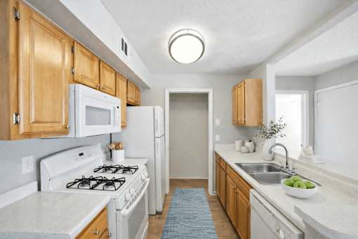 A kitchen with wooden cabinets and white appliances. at Waterbridge Apartments , Orlando