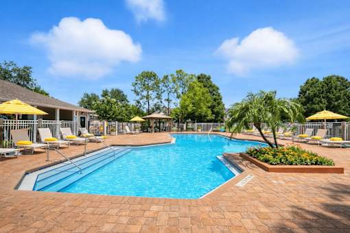 A large outdoor swimming pool surrounded by a brick patio and lounge chairs. at Waterbridge Apartments , Orlando, Florida