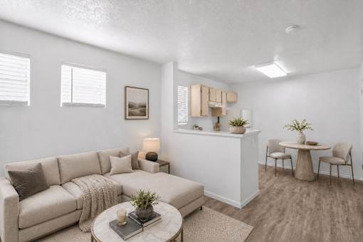 A living room with a beige couch, a coffee table, and a small dining table.