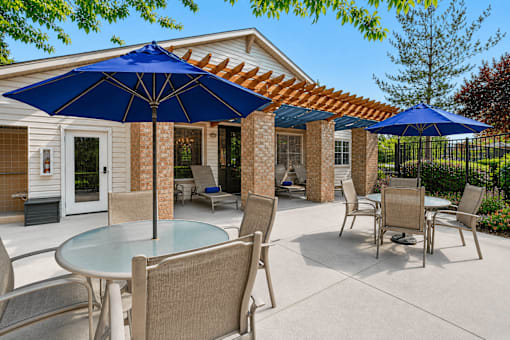 A patio with a table and chairs under blue umbrellas.