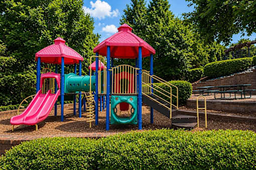 A playground with a red slide and a blue and green play structure.