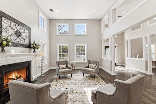 A living room with a fireplace and grey chairs.