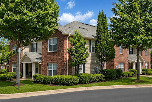 A row of red brick houses with green trees in front.