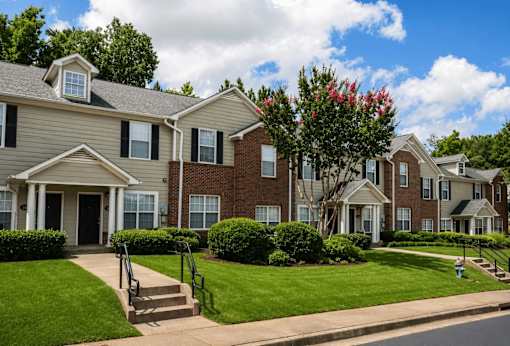 A row of houses with green lawns and trees.