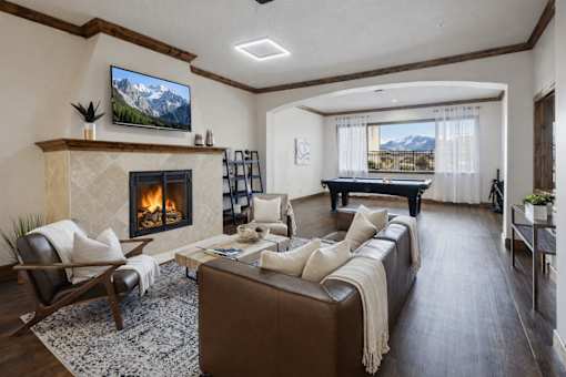 A living room with a fireplace and a large screen TV mounted on the wall.