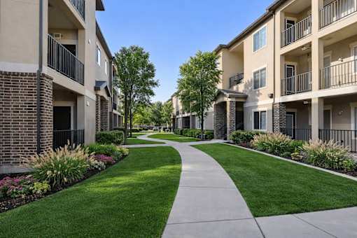 A long concrete walkway leads between two rows of apartment buildings.