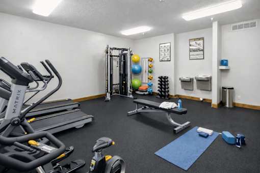 A gym with a variety of equipment including treadmills, exercise balls, and weights.