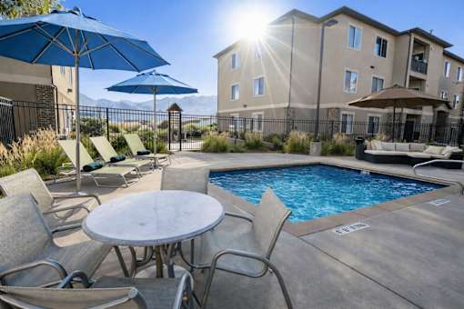 A sunny day at the poolside with chairs and umbrellas.
