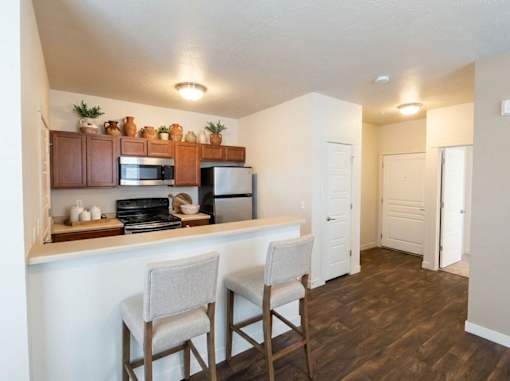 A kitchen with a white counter and brown chairs.
