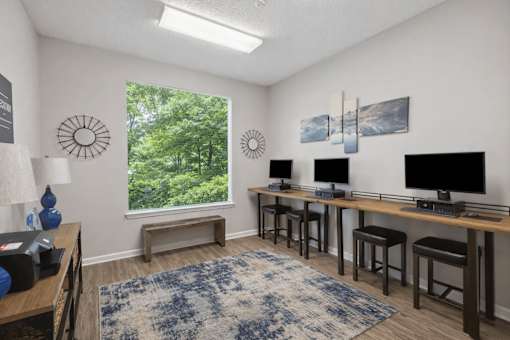 A room with a desk, chairs, and a window showing greenery outside.