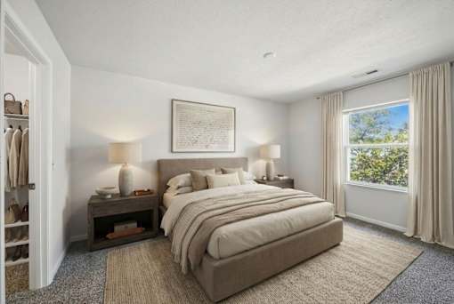A bedroom with a large bed and a window overlooking trees.