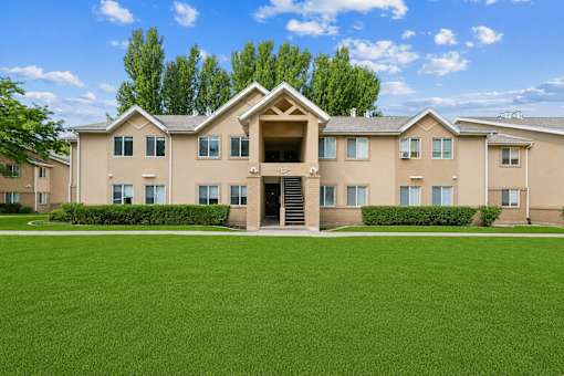 A large beige building with a green lawn in front.