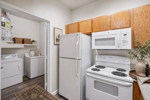 A kitchen with white appliances and wooden cabinets.