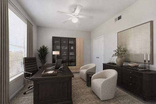 A room with a desk, chair, and a plant.