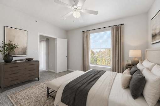 A bedroom with a large bed, a dresser, and a ceiling fan.