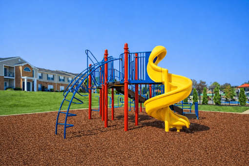 A playground with a yellow slide and a red and blue climbing structure.