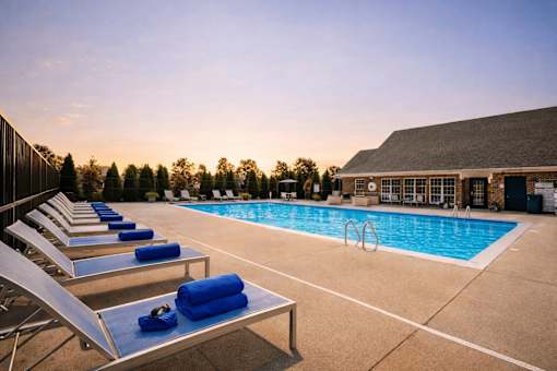 A poolside area with sun loungers and a building in the background.